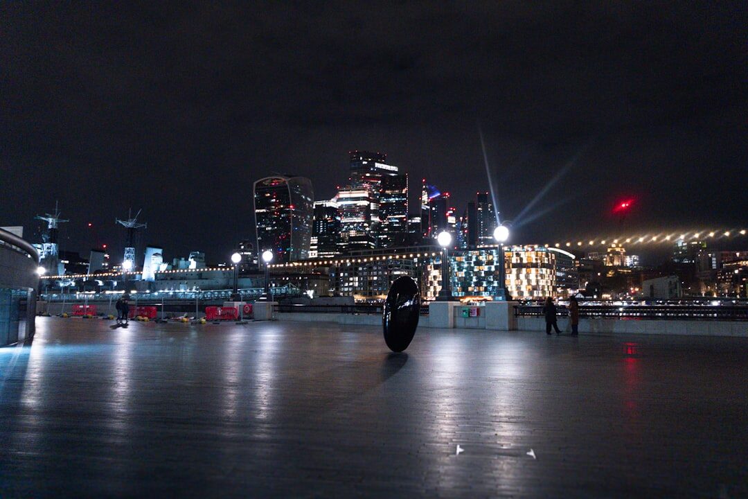 Camera operator filming a live broadcast at night with city lights